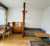 Pokoj v 3-pokojovém bytě s podlahou s dřevěným dekorem, nábytkem a dekorativními doplňky.