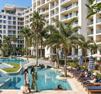 Elegantní resort s bazénem, palmami a relaxujícími hosty.