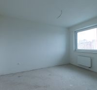 Prázdná místnost s bílými stěnami ve 2-pokojovém bytě, velké okno, radiátor.