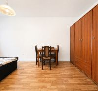 Pokoj v rodinném domě s podlahou s dřevěným dekorem, postelí, skříní a jídelním stolem.