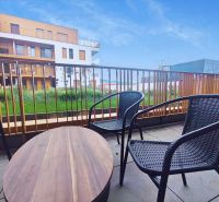 Balkon s ratanovým posezením a výhledem na architekturu Piaristické ulice v Nitře.