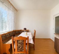 Jídelní část s rohovou lavicí, stolem, židlí a podlahou s dřevěným dekorem.