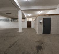 Interiér skladů a hal s masivním betonovým sloupem a šedými stěnami.