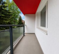 Balkon z 2pokojového bytu s červeným stropem a zábradlím se sklem.
