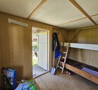 Pokoj v chatě s palandou a podlahou s dřevěným dekorem.