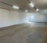 Prostorný prázdný interiér s betonovou podlahou a bílými stěnami ve skladech a halách.