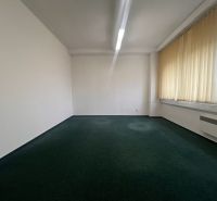 Kanceláře s kobercem a záclonami na velkých oknech.
