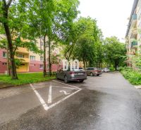 Parkoviště s auty a obytnými domy obklopené zelení v Martině.