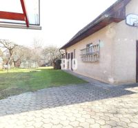 Dvůr u rodinného domu v Turanech s basketbalovým košem a zahradním skleníkem.