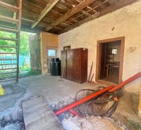 Interiér rodinného domu s dřevěným stropem, rozkopanou podlahou a žebříkem.