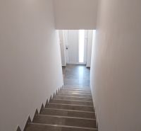 Schodiště ve 4-pokojovém bytě s dlažbou a bílými stěnami.