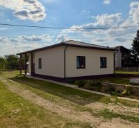 Rodinný dům v Zemplínské Široké obklopený zelení, jasná obloha nad střechou.