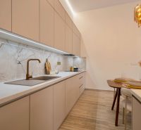 Kuchyně s elegantní pracovní deskou, moderním dřezem a dekorativním osvětlením v rodinném domě.