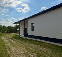 Exteriér rodinného domu v Zemplínskej Širokej obklopený trávníkem a stromy.