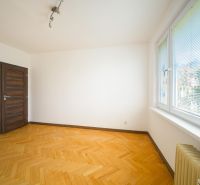 Pokoj ve 3-pokojovém bytě s podlahou s dřevěným dekorem a velkými okny.