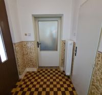 Dlažba se šachovnicovým vzorem v interiéru rodinného domu s bílými stěnami.