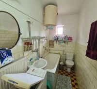 Koupelna se zrcadlem, umyvadlem, vanou a pračkou v rodinném domě.