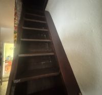 Schodiště vedoucí nahoru v rodinném domě s tmavými dřevěnými schody.