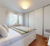 Ložnice s postelí, vestavěnou skříní a podlahou s dřevěným dekorem ve 3pokojovém bytě.