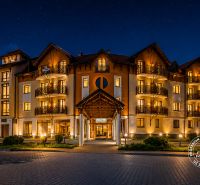 Noční scéna hotelu v krásné iluminaci s hvězdami na obloze.