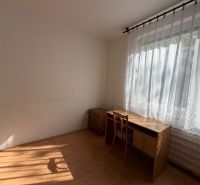 Pokoj s pracovním stolem a židlí, podlaha s dřevěným dekorem.