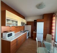 Kuchyně ve 3-pokojovém bytě s bílou linkou a podlahou s dřevěným dekorem.