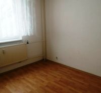 Pokoj v 3-pokojovém bytě s podlahou s dřevěným dekorem, závěsem a radiátorem.
