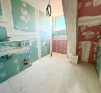 Koupelna v 2-pokojovém bytě s přípravou na instalaci, podlaha čeká na finální úpravu.
