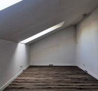 Podkrovní pokoj s podlahou s dřevěným dekorem v rodinném domě.