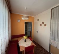 Kuchyně v 2-pokojovém bytě s oranžovou stěnou, koberec a krajkové záclony.