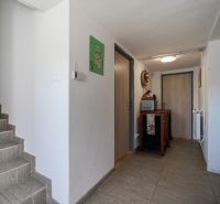 Vstupní chodba rodinného domu s podlahou s dřevěným dekorem a schodištěm.