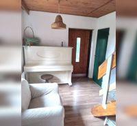 Interiér rodinného domu s bílým klavírem, podlaha s dřevěným dekorem, schody a dřevěný strop.