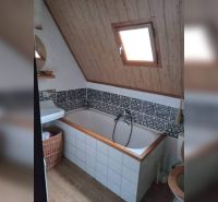 Koupelna s vanou a šikmým stropem, dřevěný dekor, mozaikový obklad, okno.