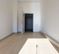 Interiér kanceláře s bílými stěnami a světlým keramickým obkladem podlahy.