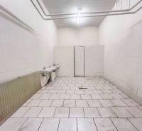 Interiér skladů a hal s bílými stěnami, dvěma umyvadly a dlaždicovou podlahou.