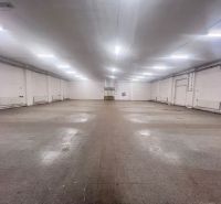 Prostorný interiér skladů a hal s osvětlením na stropě a dlažbou na podlaze.