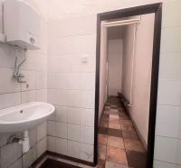 Interiér koupelny ve skladech a halách s umyvadlem a nástěnným ohřívačem vody.