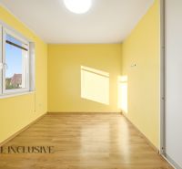 Interiér 3-pokojového bytu se žlutými stěnami a podlahou s dřevěným dekorem.