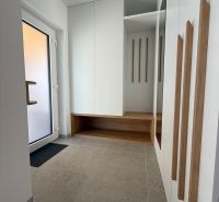 Vstupní hala v rodinném domě se zrcadlem, úložným prostorem a světlými dlaždicemi.