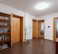 Interiér rodinného domu s dřevěnou dekorací podlahy a knihovnou.