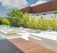 Luxusní vila na Bali s bazénem obklopeným zelení a relaxační zónou.