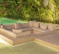 Luxusní venkovní sedačka obklopená tropickou zelení u bazénu ve vile na Bali.