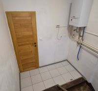 Schodiště s dřevěnými stupni a plynovým kotlem v 2pokojovém bytě.