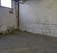 Průmyslový interiér s opotřebovanými stěnami a šedou podlahou, sklady a haly.
