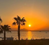 Západ slunce s palmami a mořem v La Manga del Mar Menor, Španělsko.
