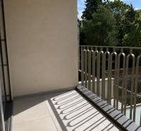Balkón se zábradlím a výhledem na zeleň v 2-pokojovém bytě.