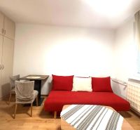 Pokoj v rekreačním apartmánu s červenou pohovkou, stolem a podlahou s dřevěným dekorem.