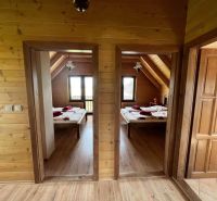 Interiér chaty s dvěma ložnicemi, dřevěnými stěnami a podlahou s dřevěným dekorem.