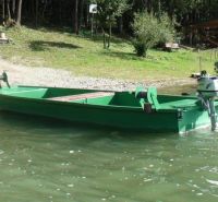 Zelený člun na vodě u břehu v Liptovské Sielnici, obklopený zelení a stromy.