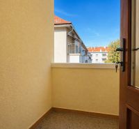 Balkon ve 4pokojovém bytě s výhledem na střechy a stromy.